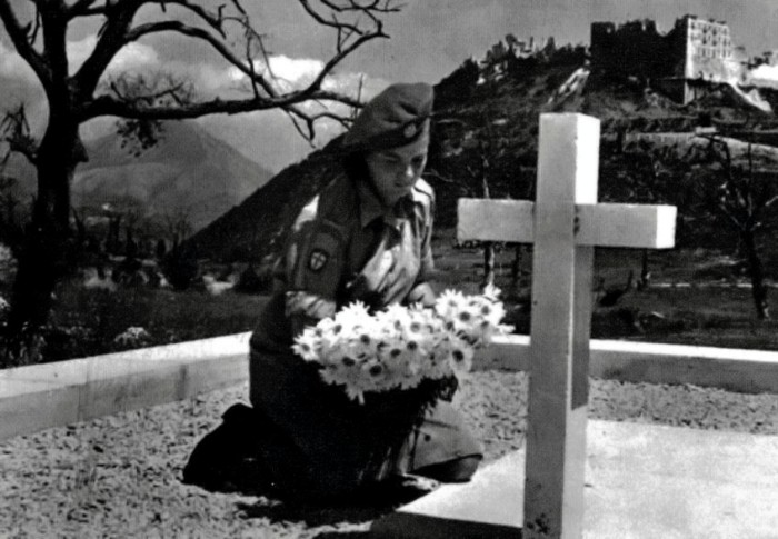 Dziewczyna z Pomocniczej Służby Kobiet składa kwiaty na grobie poległego żołnierza.